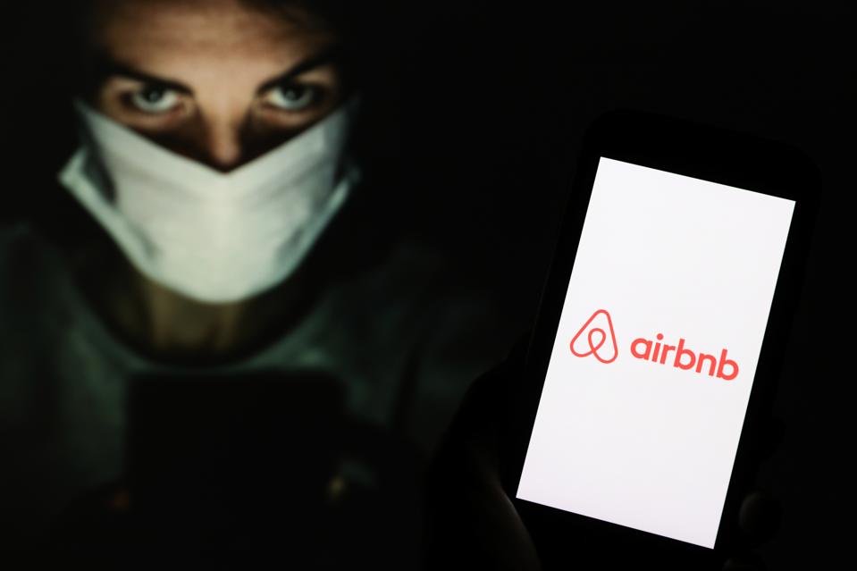 In this photo illustration an Airbnb logo seen displayed on...