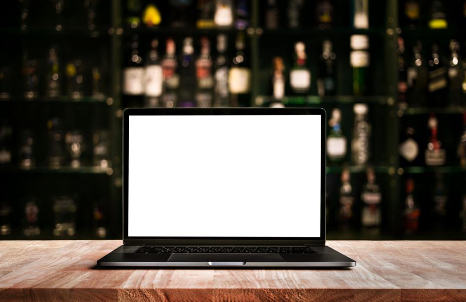 Modern computer,laptop on counter bar with blur wine bottle