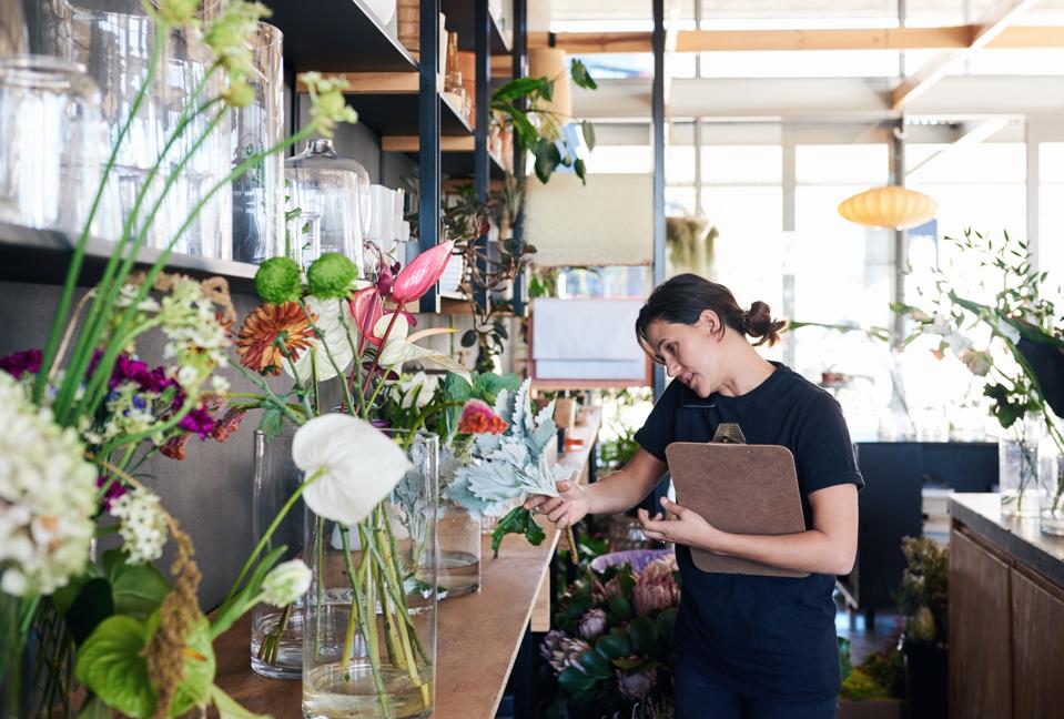 Florist standing in her flower shop talking on the phone