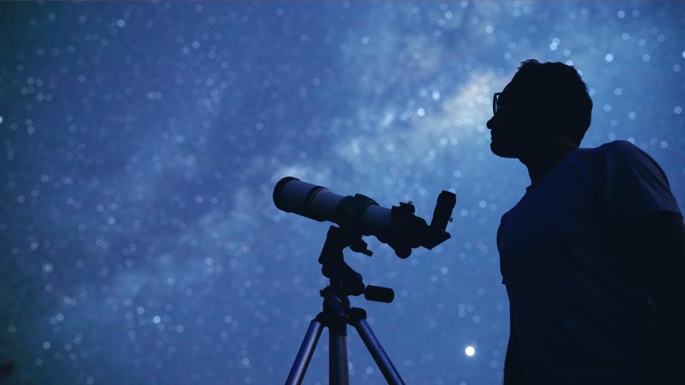 Astronomer with a telescope watching at the stars and Moon.