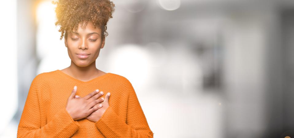Beautiful young african american woman over isolated background smiling with hands on chest with closed eyes and grateful gesture on face. Health concept.