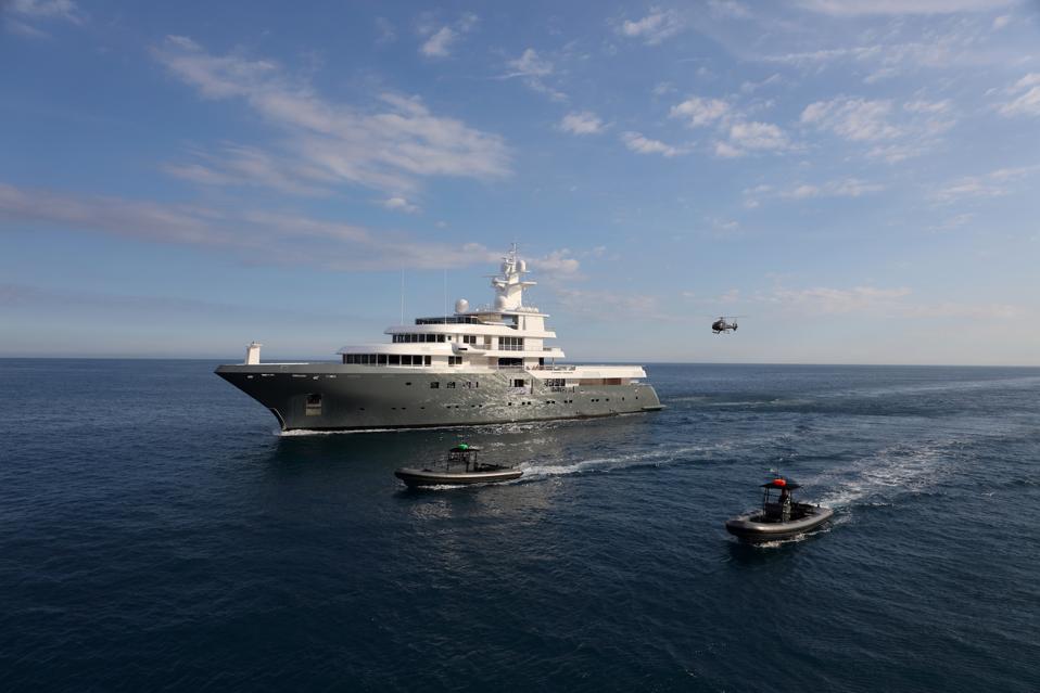 Planet Nine superyacht sails on the ocean, accompanied by custom tenders and a helicopter