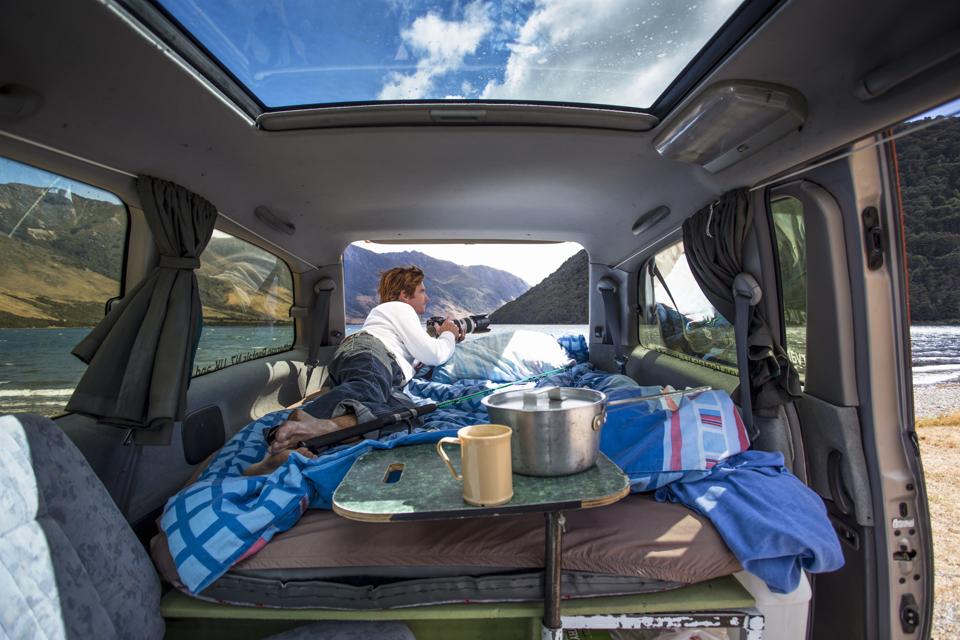 A man sits in his campervan at a camp.