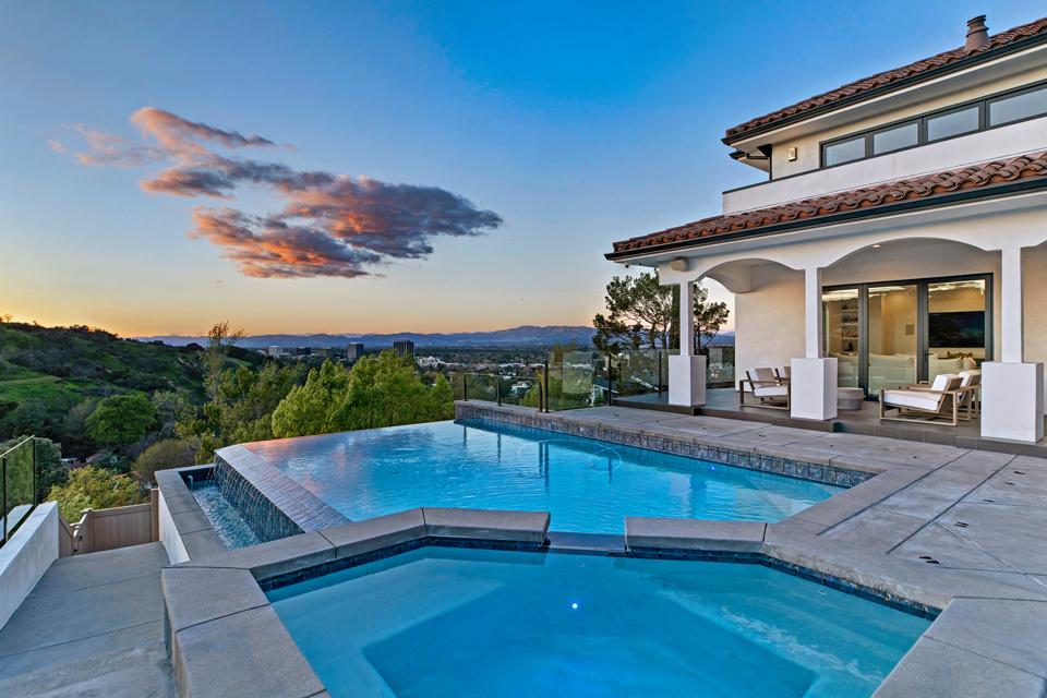 A swimming pool and spa with a valley view in the background.