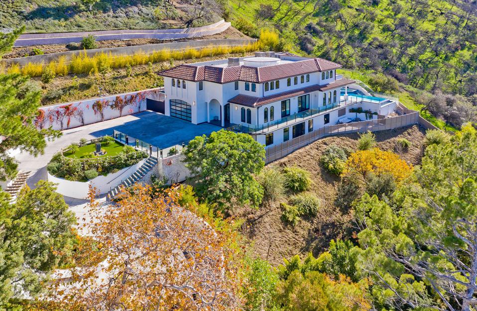 A house on a hill surrounded by trees and landscaping.