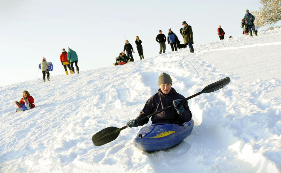 A man uses a kayak to slide down a farme