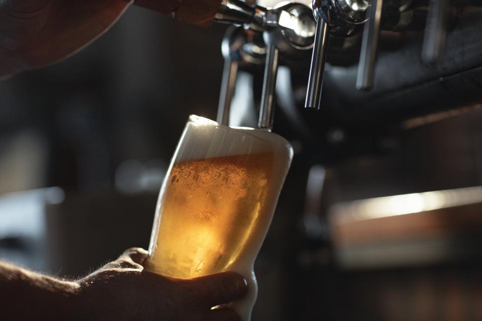 A person filling up a pint of beer from a tap.