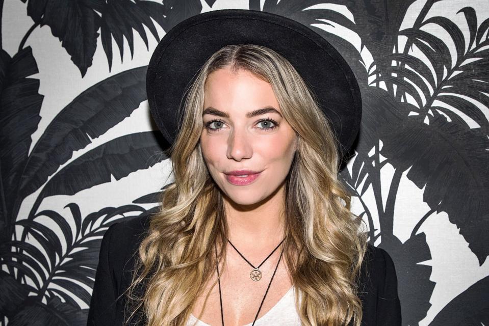 Headshot of Megan in front of black and white background wearing a hat.