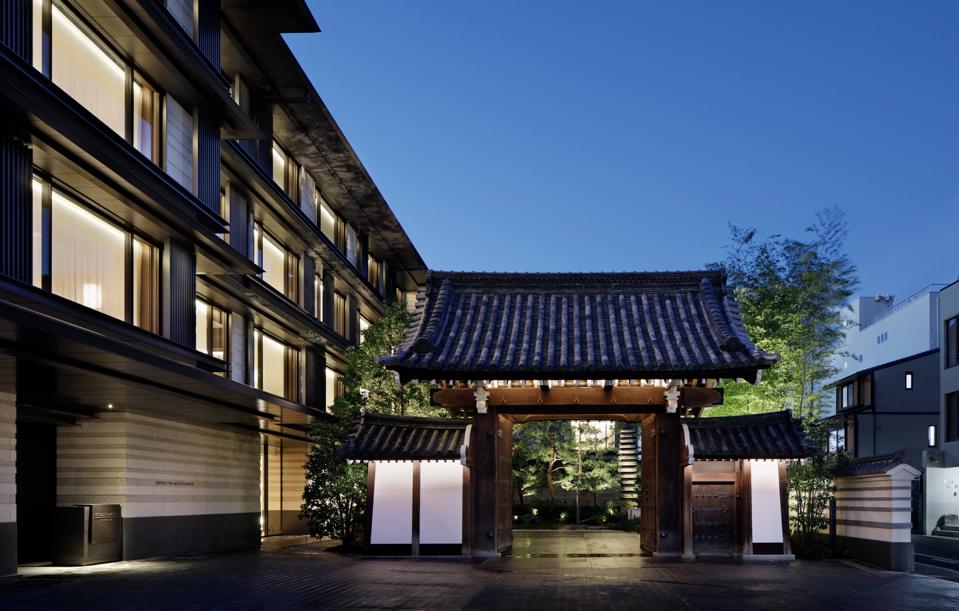 A pagoda shaped Japanese gate next to a modern building.