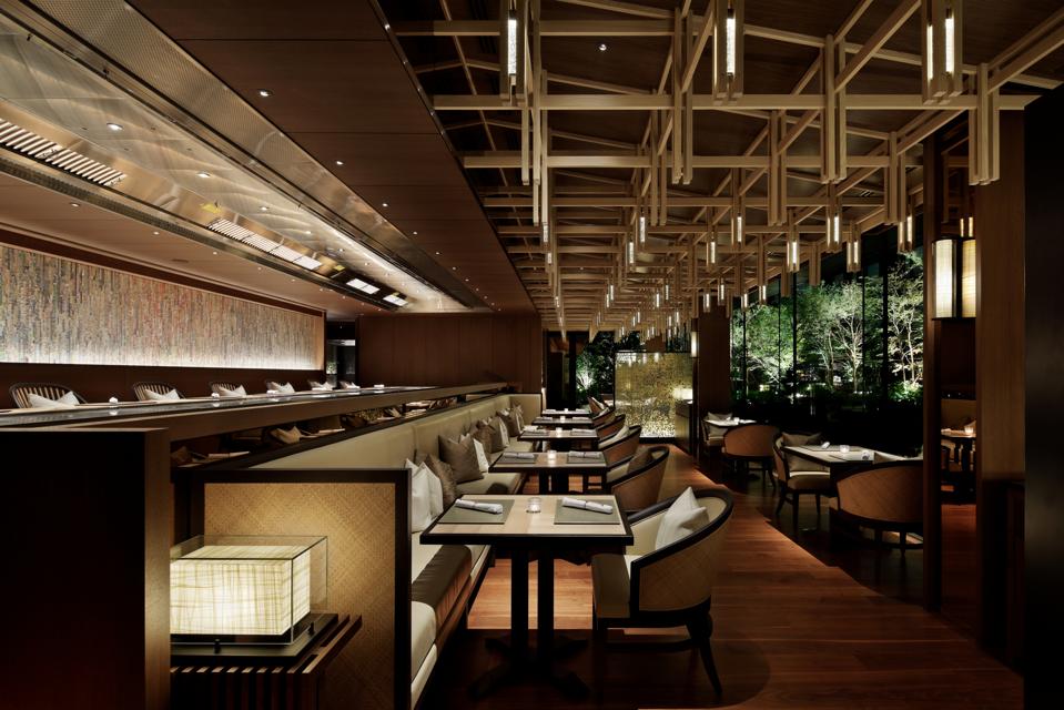 A long, sleek brown and brown toned room with greenery outside