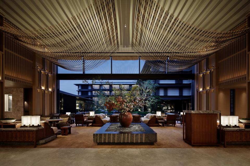 An expansive room with a golden sweep of rods draped from the ceiling overlooking the outdoors