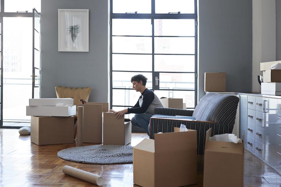 Woman wrapping boxes in stylish apartment
