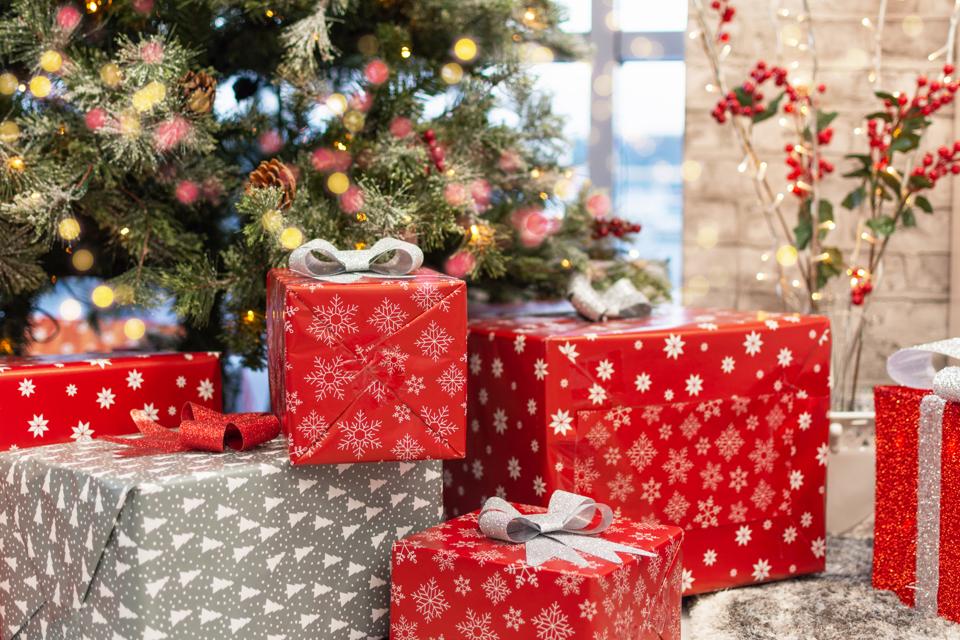 Gift boxes under Christmas tree, New Year home decorations, red wrapping Santa presents, fir tree decorated, beautiful bokeh of garland.