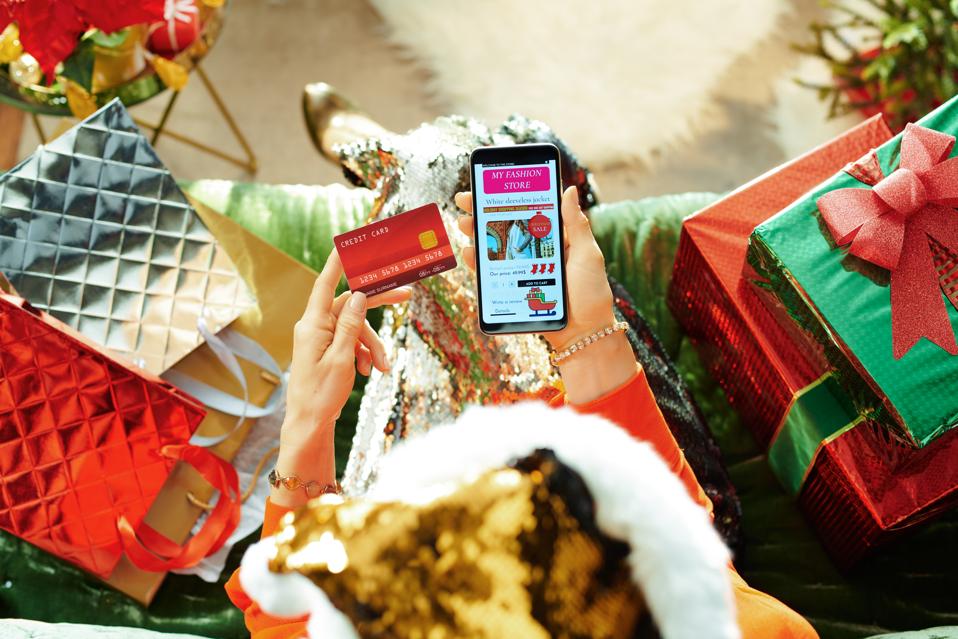 modern female buying clothes online in room at Christmas
