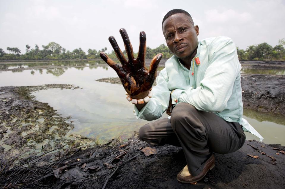 Nigerian farmer Eric Dooh shows his hand covered with oil found in his fish pond.