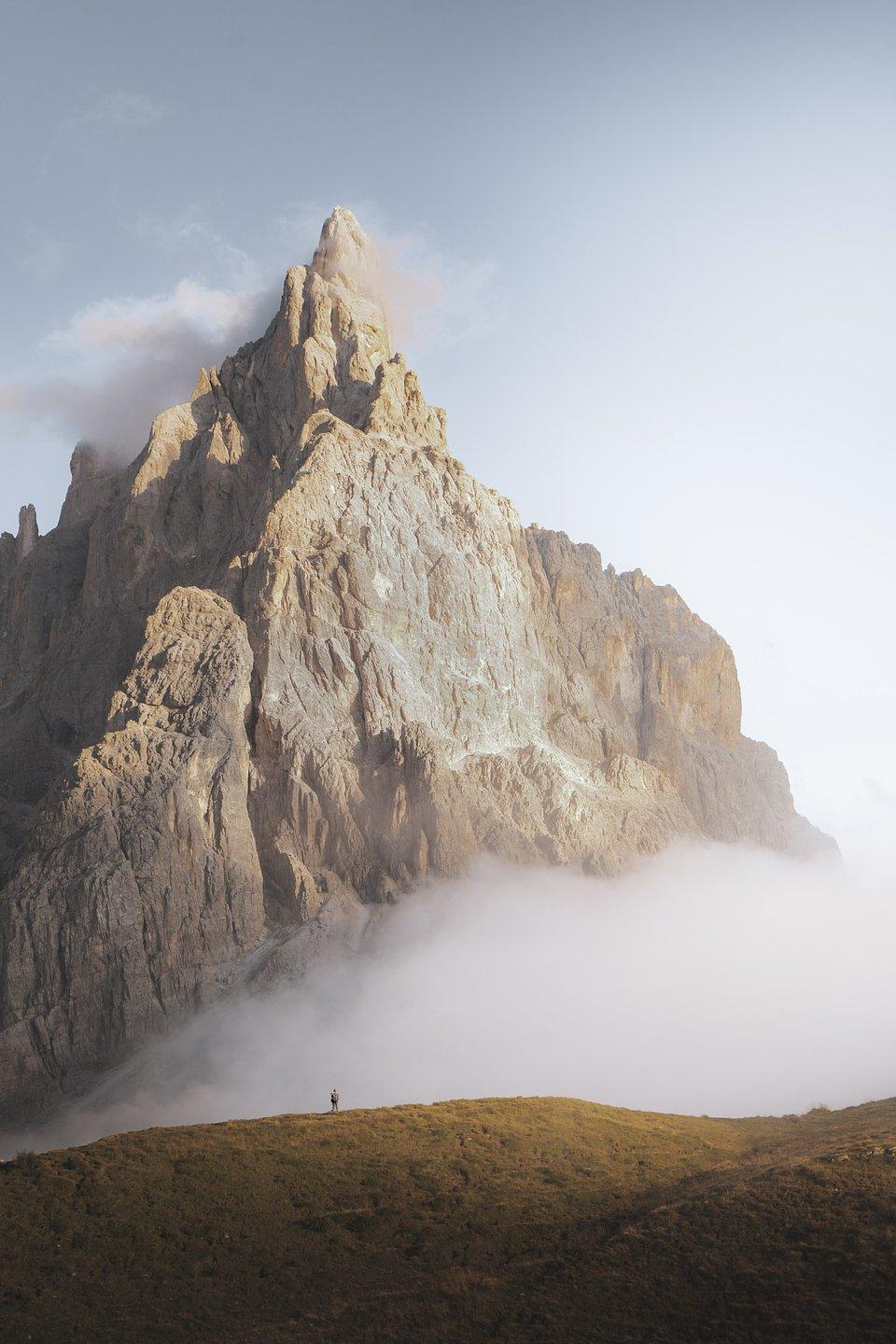 A small figure walking along an immense Dolomite Mountain ridge.