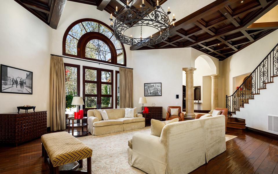 A two-story living room with a wrought-iron chandelier and palladian-style windows.