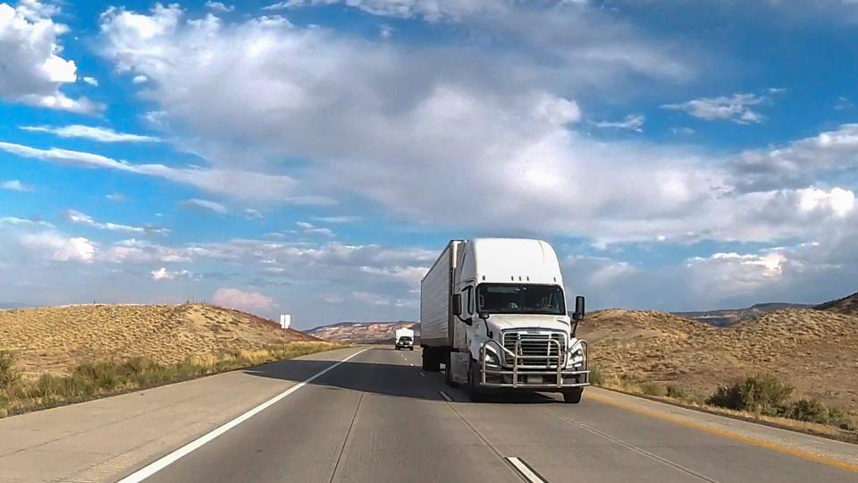 Long-Haul Semi Trailer Truck Big Rig Moving on a Four-Lane Highway under a Dramatic Sunset Cloudscape in the American West