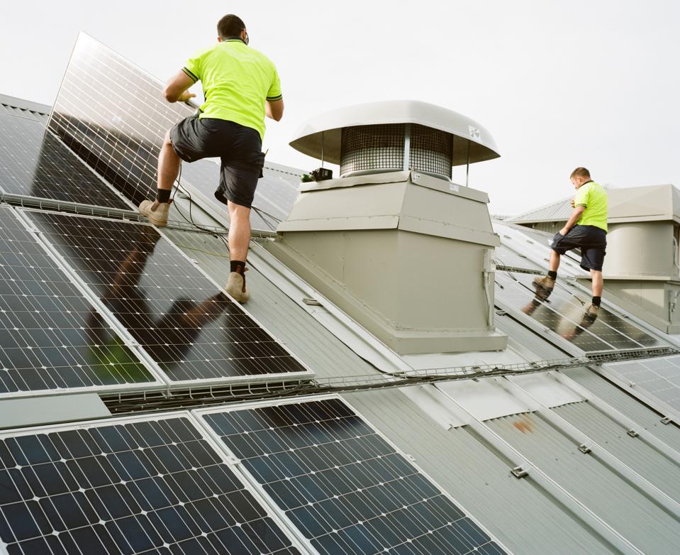 Two men installing solar panels on roof