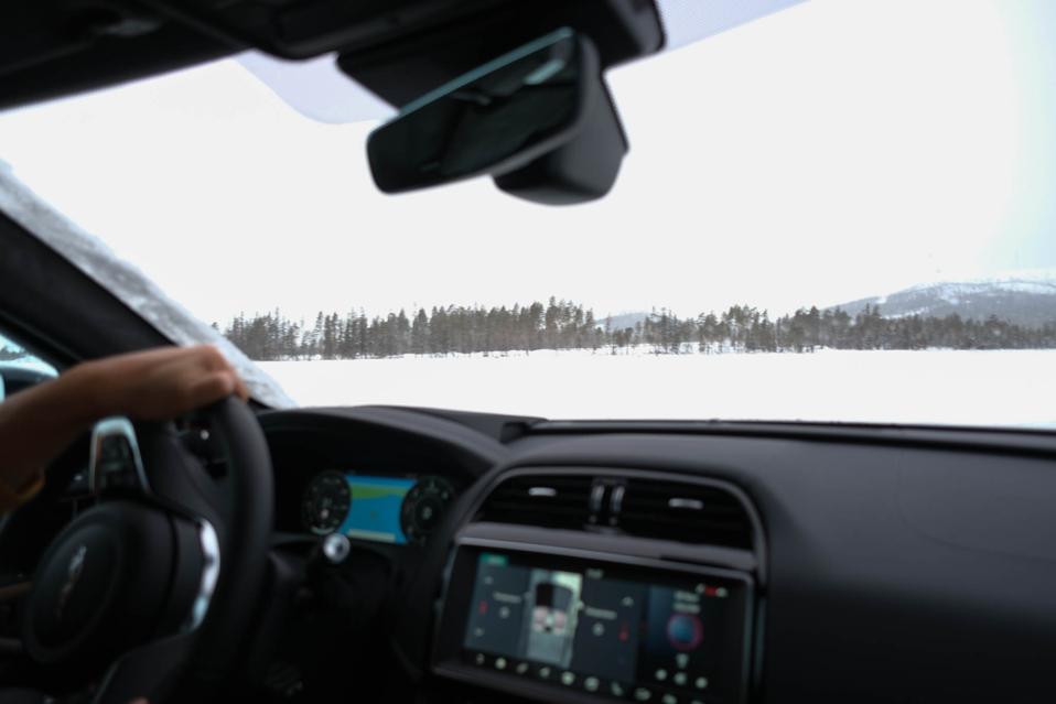 car on frozen lake hands on steering wheel