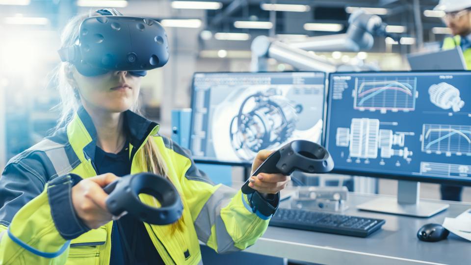 HOW HONEYWELL’S LATEST VR-BASED SIMULATOR BORROWS FROM GAMING TO TRANSFORM INDUSTRIAL TRAINING WOMAN WEARING VIRTUAL REALITY HEADSET AND USING CONTROLLERS, STANDING IN FRONT OF COMPUTERS