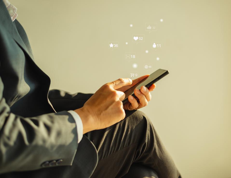 Midsection Of Man Using Mobile Phone Against Gray Background