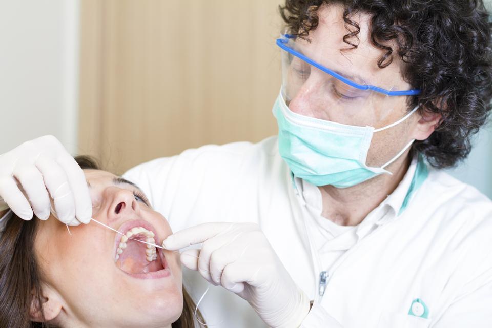 Dentiste au travail avec du fil dentaire