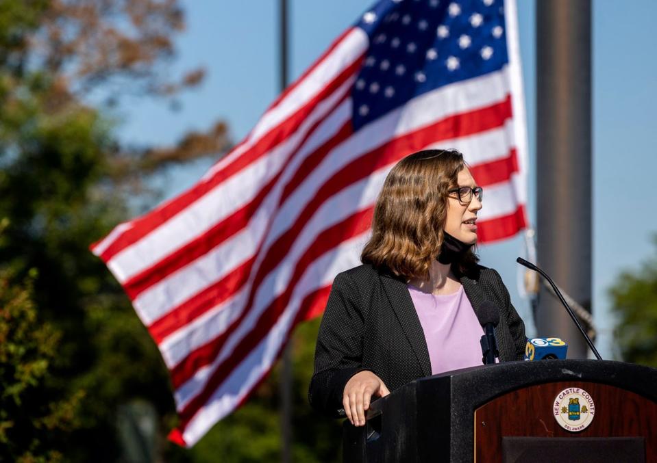 A woman at a podium in front of an American flag,