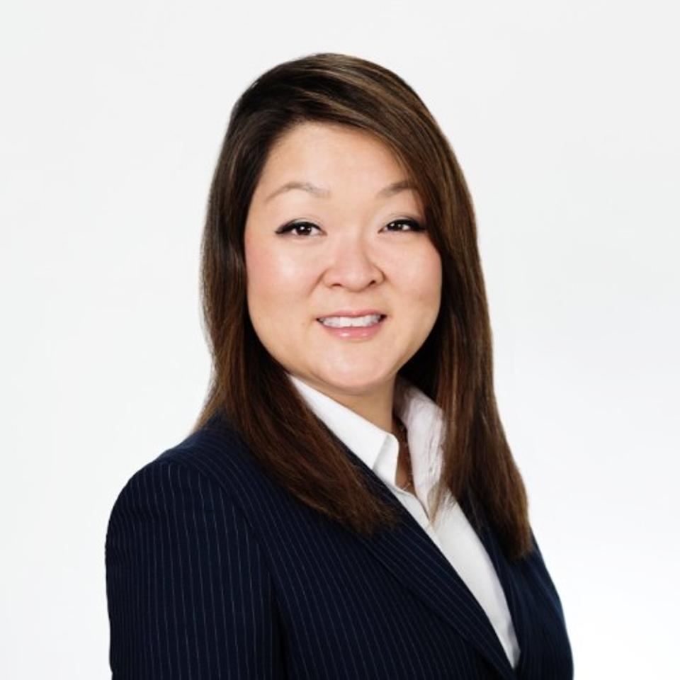Headshot of a woman with brown hair wearing a pinstriped suit jacket and white shirt