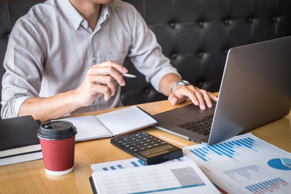 Midsection Of Businessman Analyzing Data Over Laptop On Desk