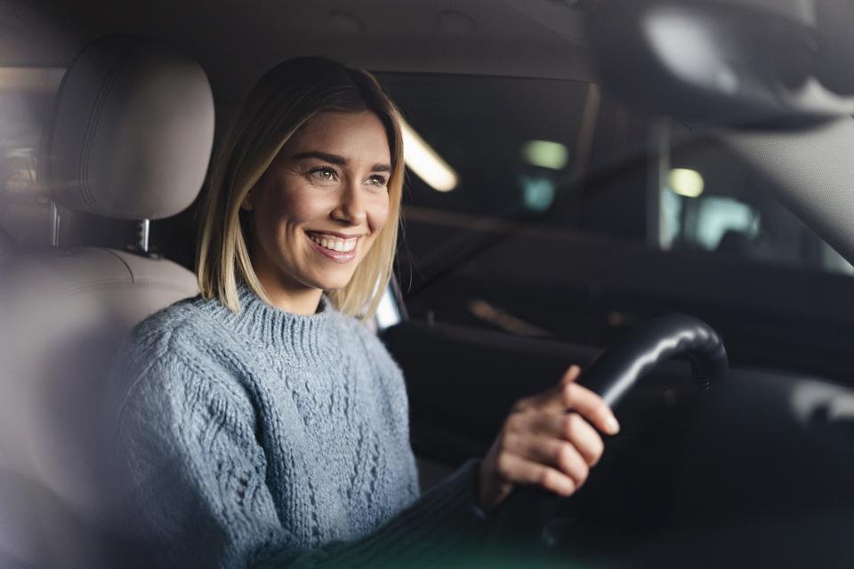 Portrait of happy young woman driving a car