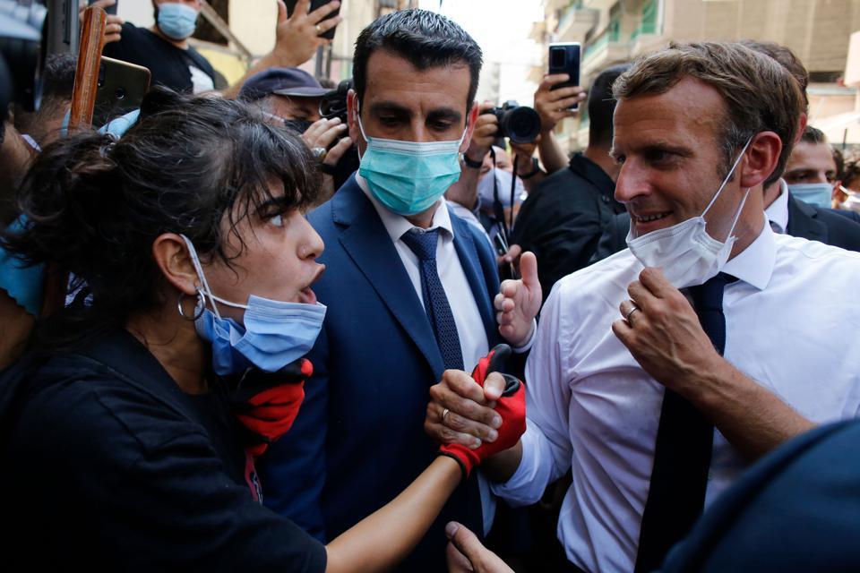 French President Emmanuel Macron listens to a resident as he visits a devastated street of Beirut, Lebanon, on August 6, 2020 a day after a massive explosion devastated the Lebanese capital in a disaster that has sparked grief and fury.
