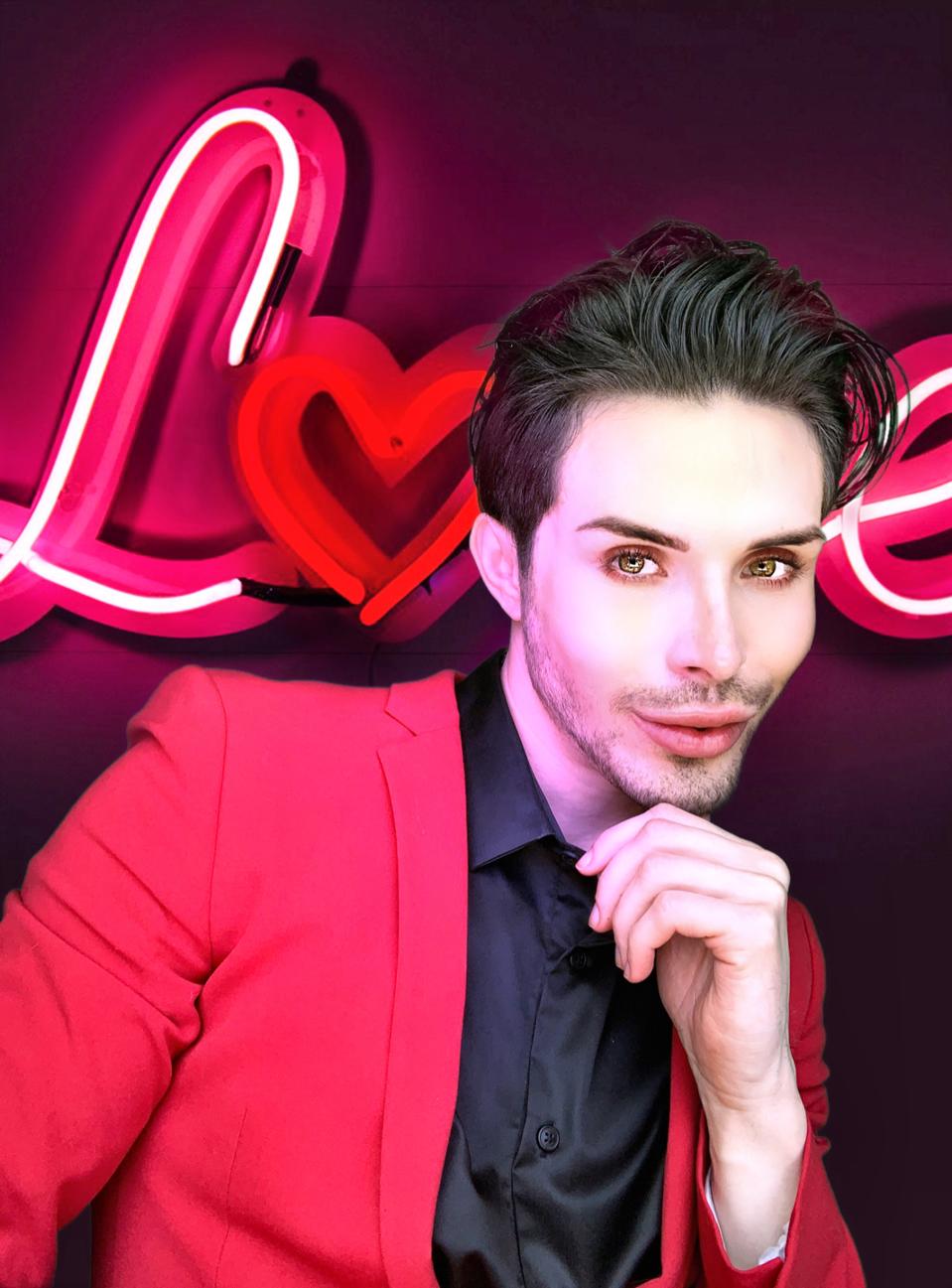 Brandan Rader looks into the camera in front of a neon sign that says LOVE.