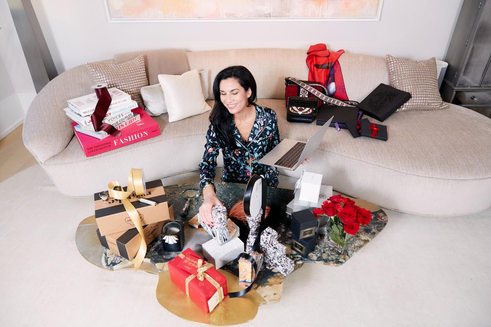 Elisabeth Jones-Hennessey of Gift Me Chic, an online gifting destination sitting in her living room surrounding by gifts.