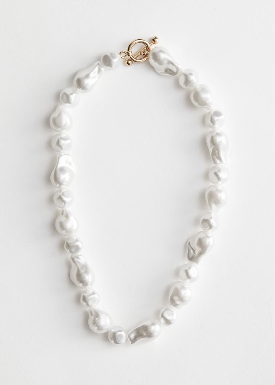 Iridescent organic pearl pendant necklace with a short fit and gold-toned metallic O-ring and bar closure.