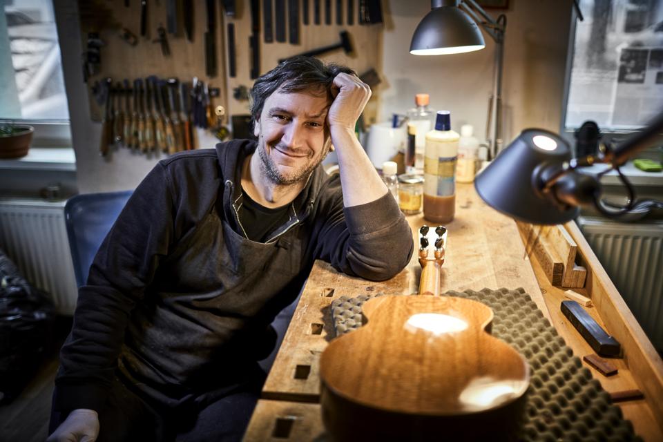 Portrait of smiling instrument maker sitting in his workshop