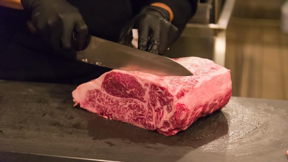 someone cutting into a slab of wagyu beef at J-Spec