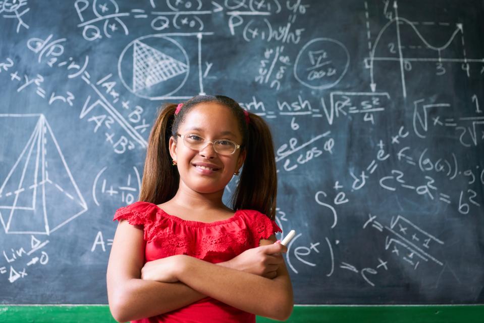 Portrait d'une jeune fille heureuse résolvant un problème mathématique complexe au tableau