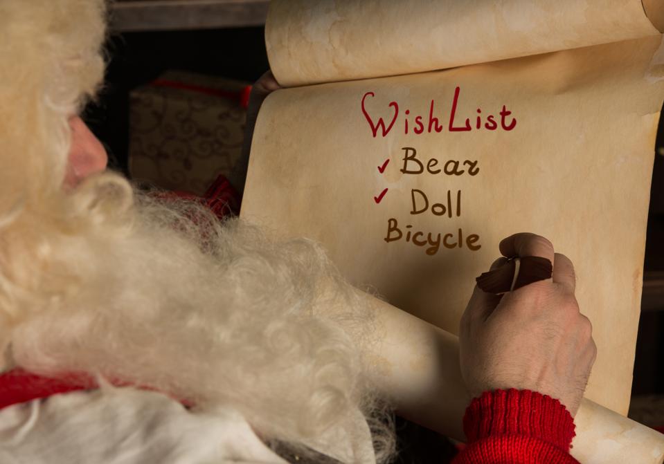 Santa Claus sitting at home and writing on paper roll