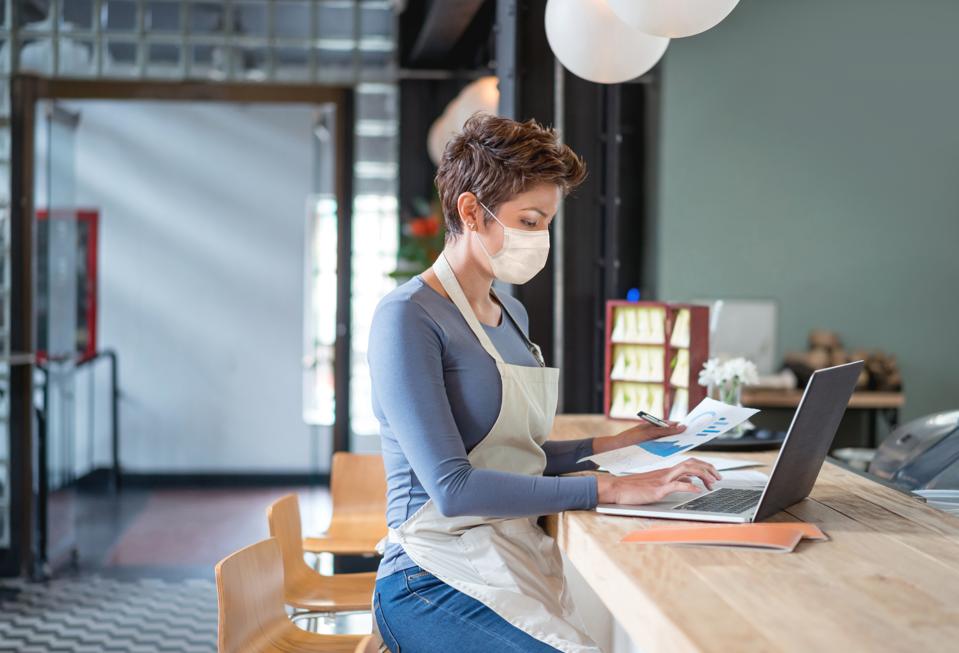Business owner wearing a facemask while bookkeeping at a restaurant