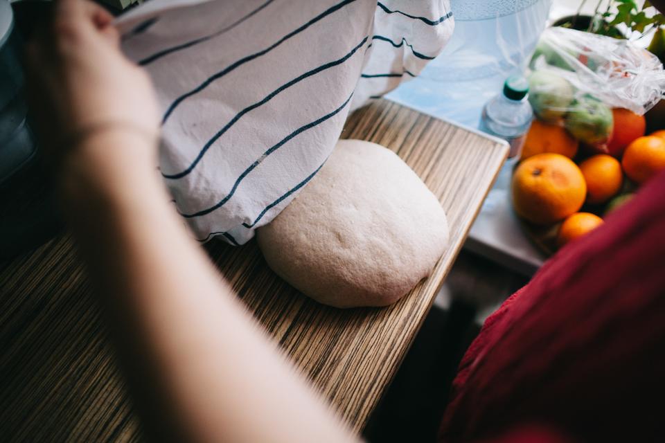 close-up of the hands of young man holding the towel above the dough with cooking machine