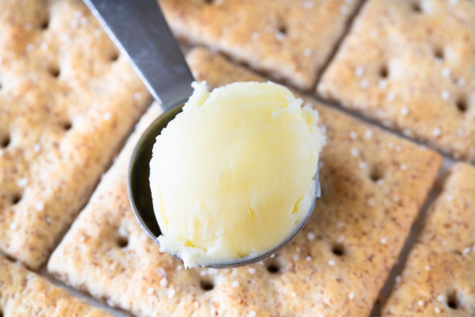 A small scoop with butter over a group of soda crackers.
