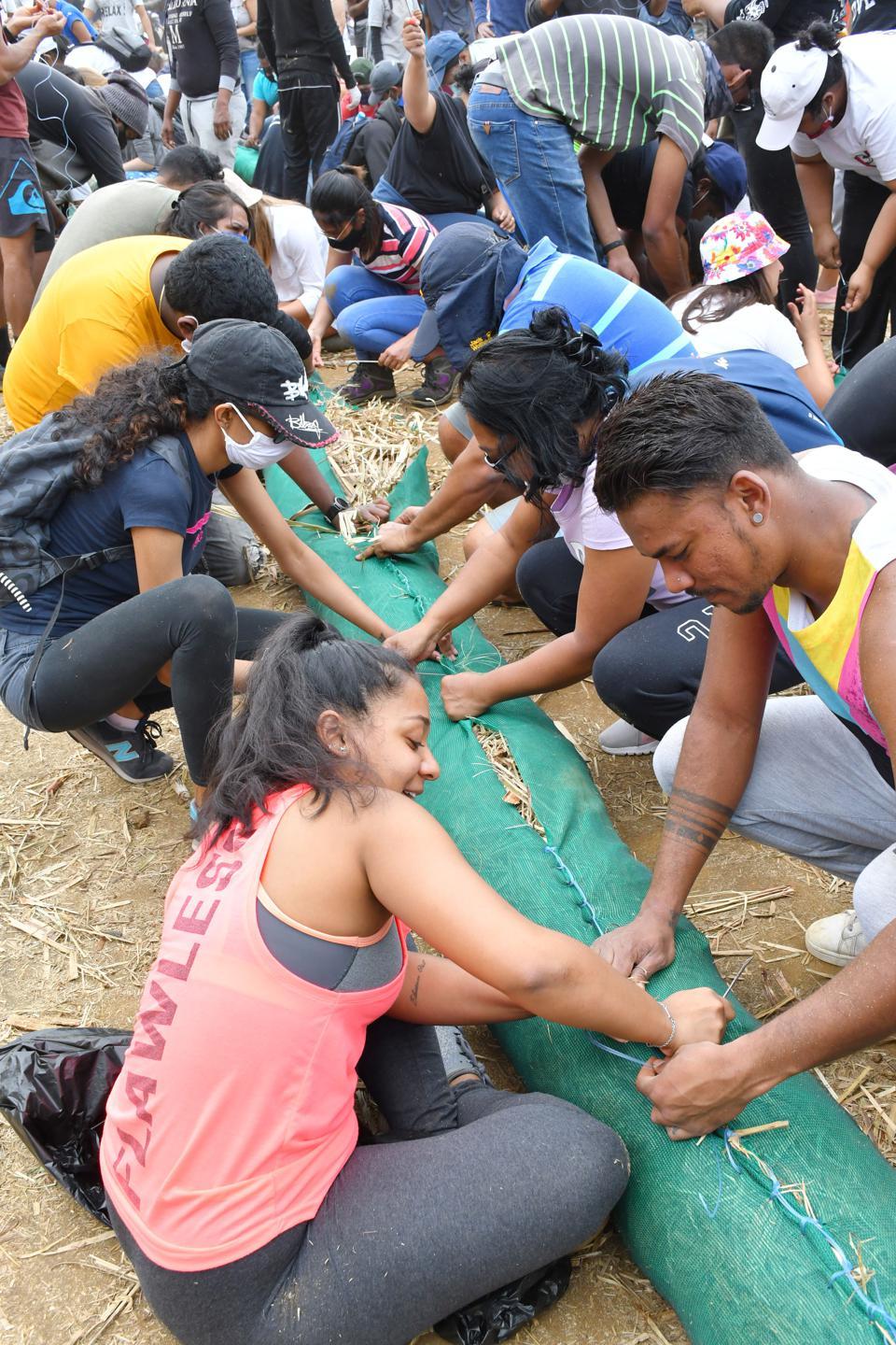 Volunteers make a nylon net to help prevent the spread of an oil spill in Mahebourg, Mauritius, on Aug. 8, 2020.