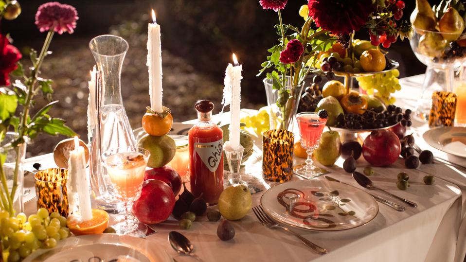 A candlelit dining table is decorated with flowers and fruit.