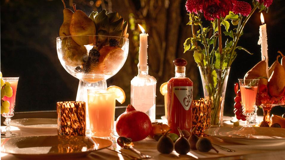 An intimate dining table is decorated with flowers, fruit, and candles.