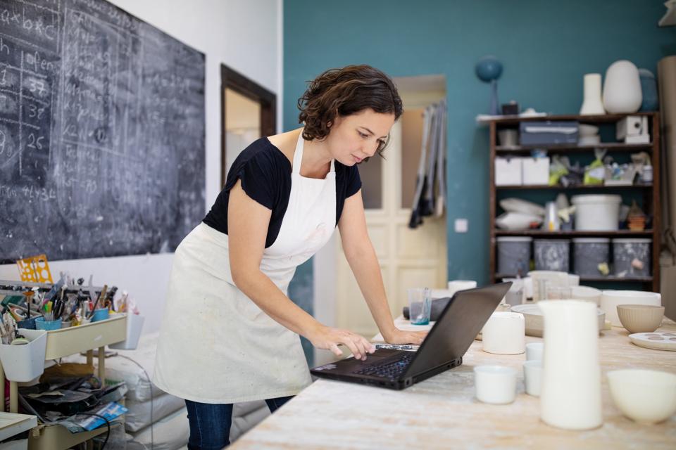 Pottery artist working on laptop at her workshop