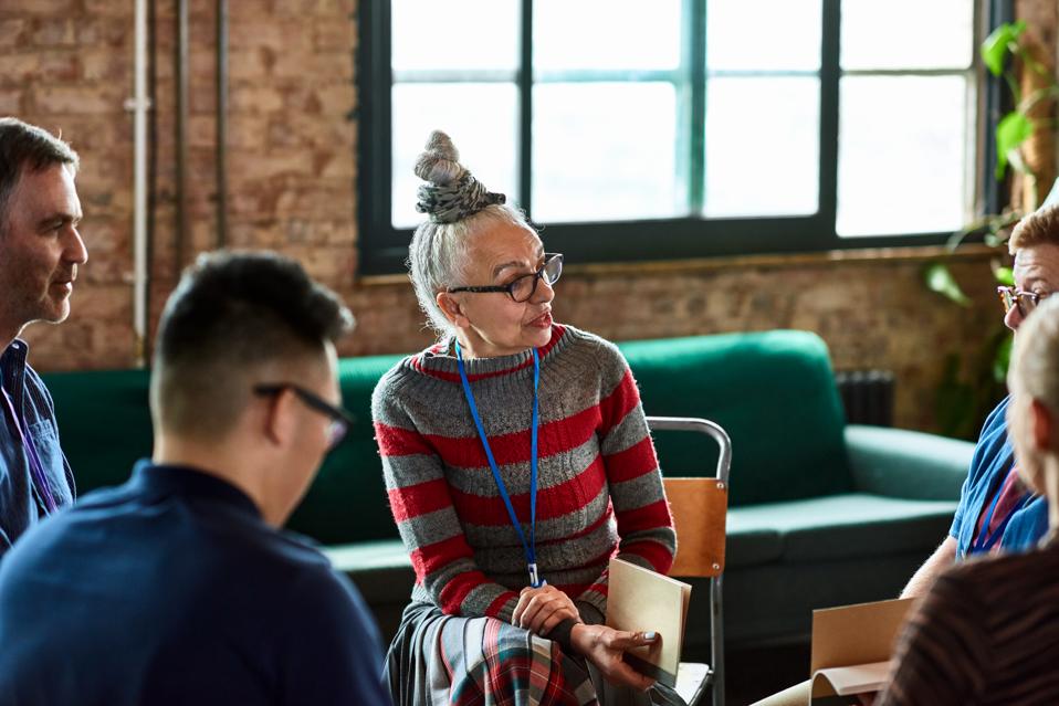 Senior woman talking to small group in office training session