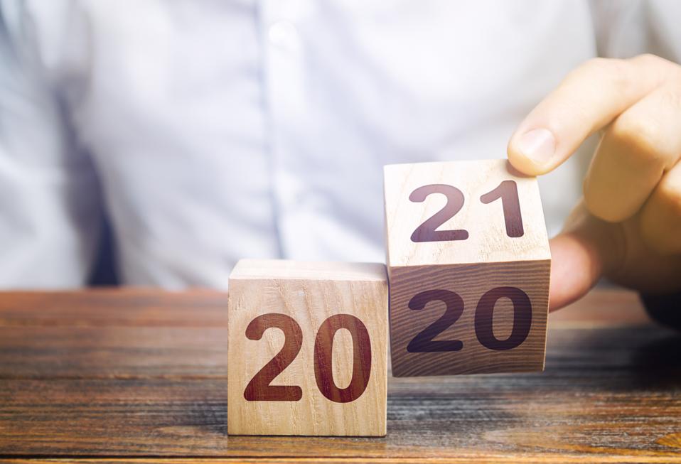 Hand flips a block changing 2020 to 2021. New year beginning.