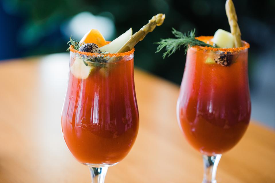 Two Bloody Marys garnished with pickled asparagus and lime wedges.