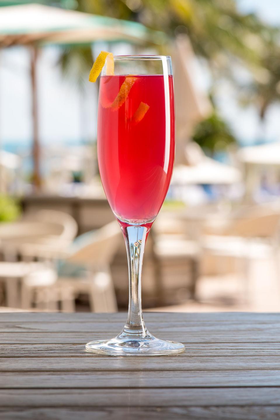 Champagne cocktail with beach backdrop.